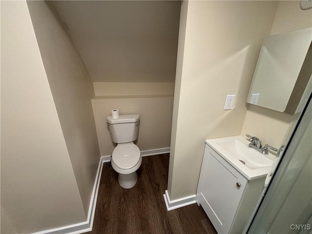 bathroom featuring toilet, wood finished floors, vanity, baseboards, and vaulted ceiling