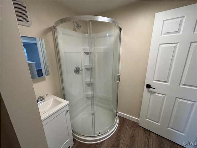 full bath featuring visible vents, a shower stall, vanity, wood finished floors, and baseboards