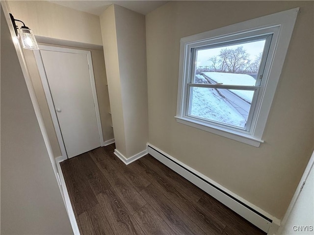 interior space with a baseboard heating unit, dark wood-type flooring, and baseboards