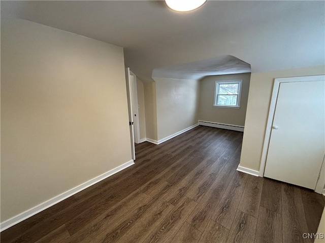 bonus room with dark wood-type flooring, a baseboard radiator, and baseboards