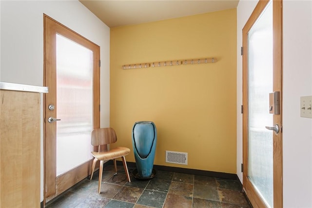 exercise room featuring stone finish flooring, visible vents, and baseboards