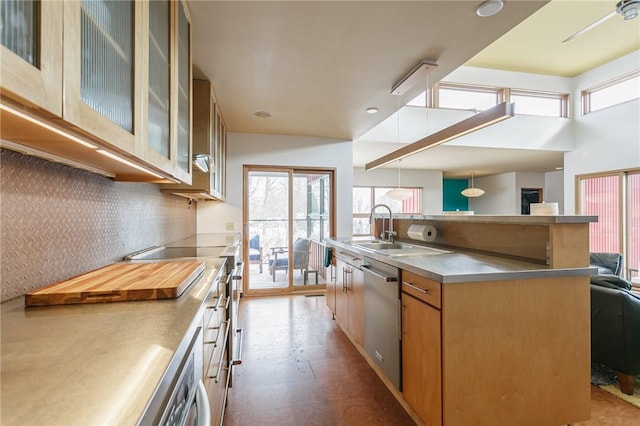 kitchen featuring tasteful backsplash, appliances with stainless steel finishes, glass insert cabinets, open floor plan, and a sink