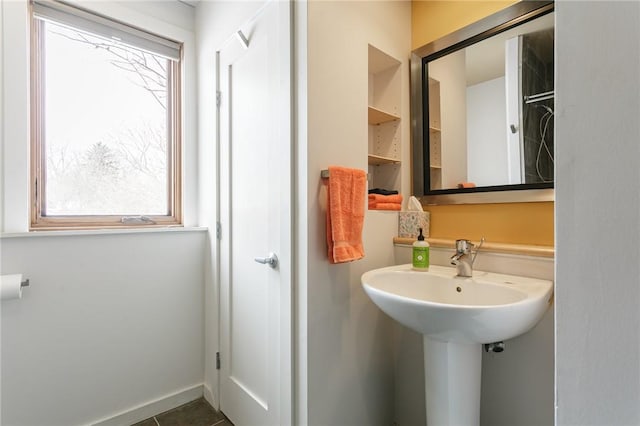 bathroom featuring tile patterned flooring, baseboards, and a sink