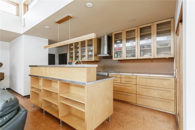 kitchen featuring hanging light fixtures, wall chimney range hood, a center island, open shelves, and glass insert cabinets