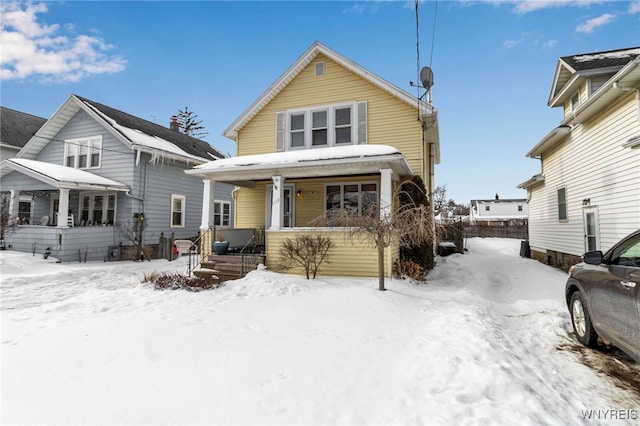 snow covered back of property with covered porch