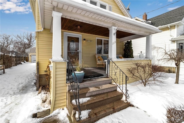 snow covered property entrance featuring a porch