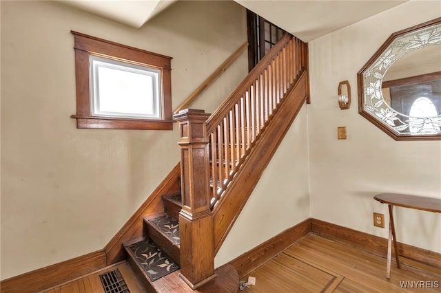 stairs featuring wood finished floors and baseboards