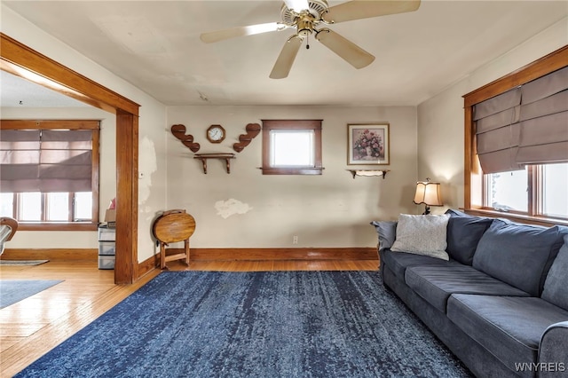 living room with ceiling fan, baseboards, and wood finished floors