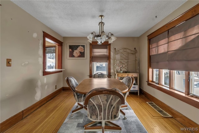 dining area with light wood-style floors, a healthy amount of sunlight, visible vents, and a notable chandelier