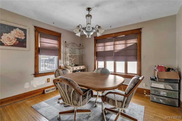 dining space featuring a chandelier, light wood finished floors, visible vents, and baseboards