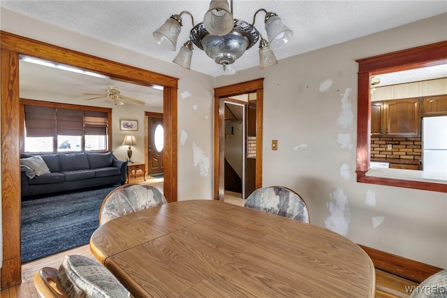 dining area featuring a textured ceiling, light wood-type flooring, and a ceiling fan