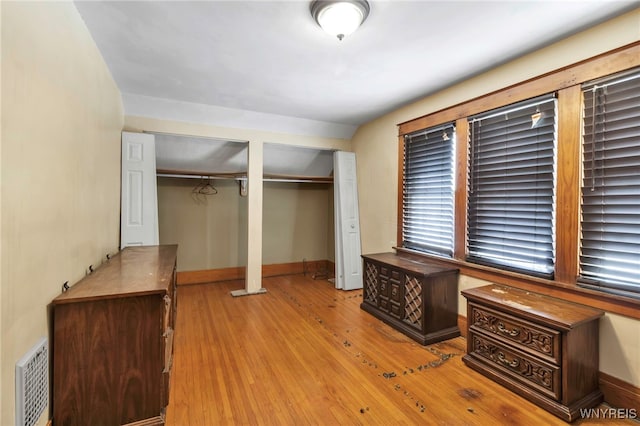 unfurnished bedroom featuring baseboards, light wood-type flooring, visible vents, and multiple closets