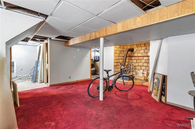 finished basement featuring a paneled ceiling, baseboards, and light colored carpet