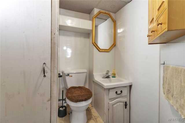 bathroom featuring vanity, toilet, and tile walls