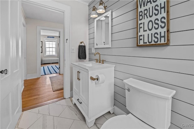 bathroom with marble finish floor, toilet, vanity, and radiator heating unit