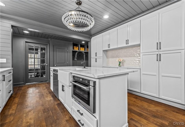 kitchen with a center island with sink, white cabinetry, stainless steel appliances, and decorative light fixtures