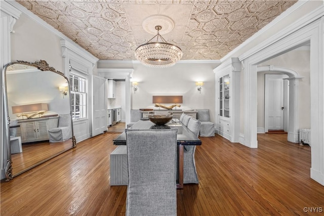 dining room with arched walkways, radiator, an ornate ceiling, crown molding, and a notable chandelier