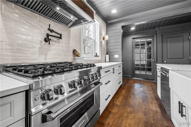 kitchen featuring dark wood-style flooring, white cabinetry, appliances with stainless steel finishes, custom exhaust hood, and decorative backsplash