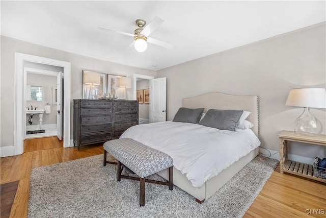 bedroom with ensuite bath, wood finished floors, a ceiling fan, and baseboards