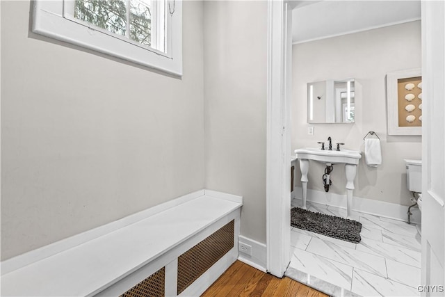 bathroom with toilet, marble finish floor, and baseboards