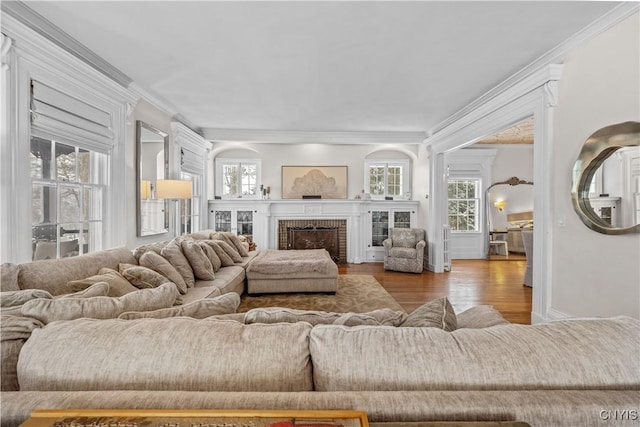 living area featuring a fireplace, wood finished floors, and crown molding