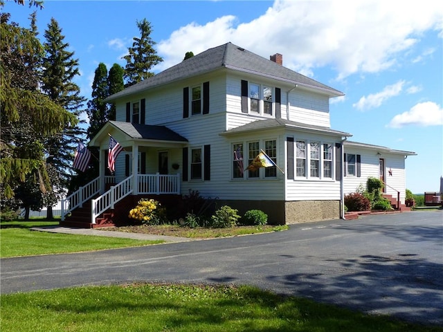 view of side of home with a chimney and a porch