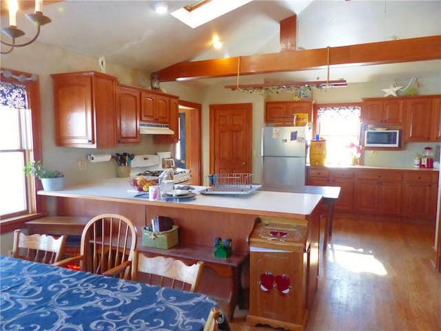 kitchen featuring decorative light fixtures, freestanding refrigerator, white gas range, light countertops, and under cabinet range hood