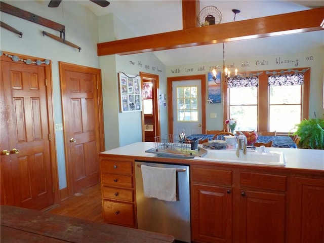 kitchen with pendant lighting, light countertops, brown cabinetry, a sink, and dishwasher