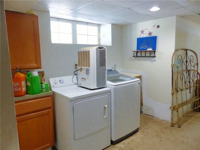 clothes washing area featuring cabinet space and washing machine and clothes dryer