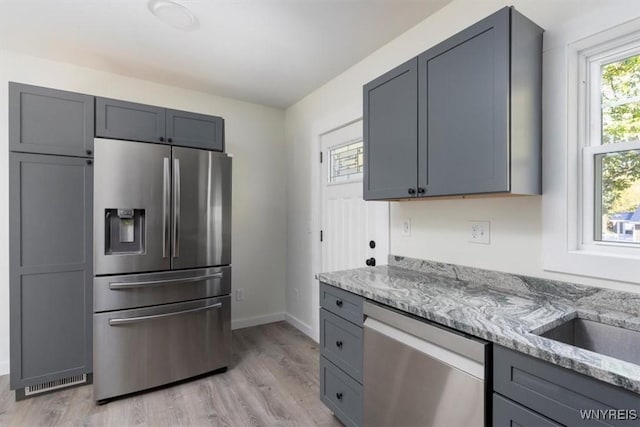 kitchen with stainless steel appliances, gray cabinets, and light stone counters