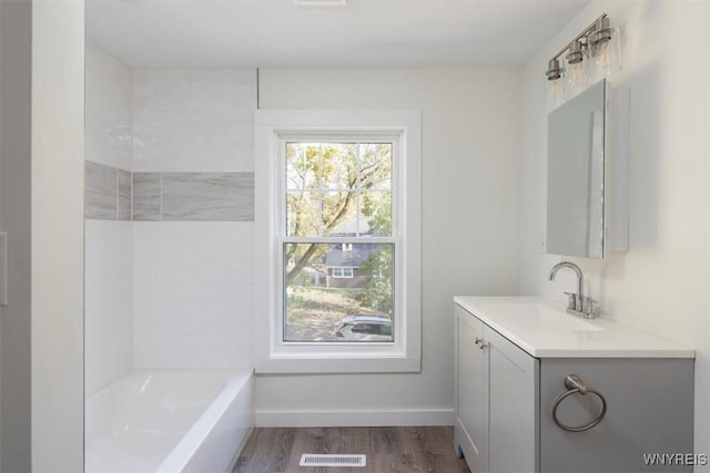 full bathroom with visible vents, vanity, baseboards, and wood finished floors