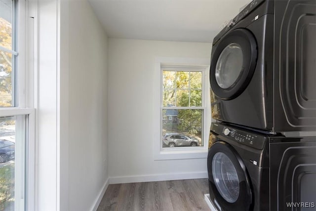 laundry room with stacked washer and dryer, laundry area, a wealth of natural light, and wood finished floors