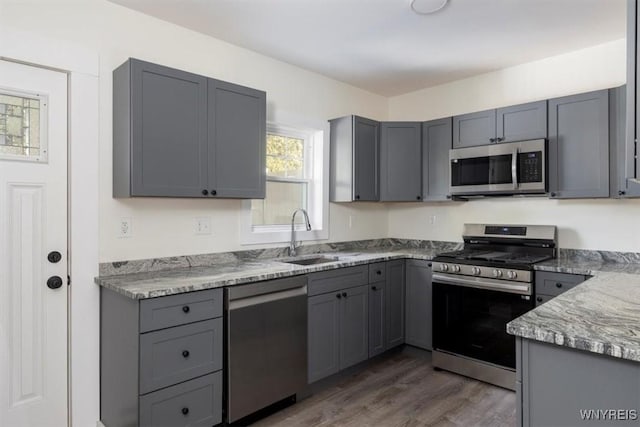 kitchen with gray cabinets, stainless steel appliances, and a sink