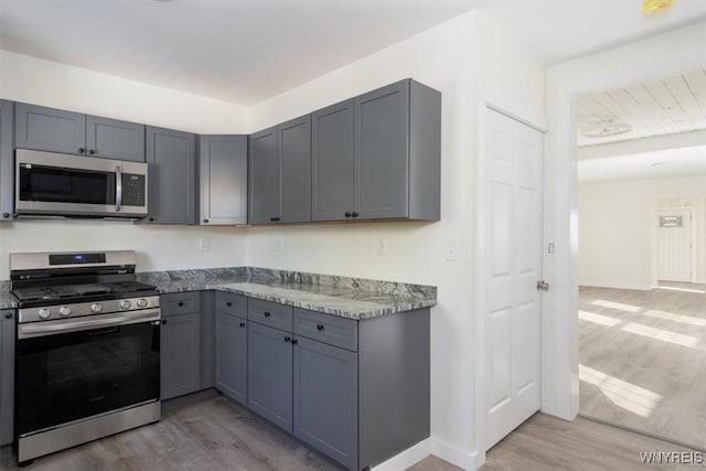 kitchen with stainless steel appliances, gray cabinets, and wood finished floors