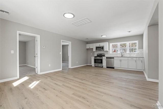 kitchen featuring light wood-style floors, white cabinetry, appliances with stainless steel finishes, and light countertops