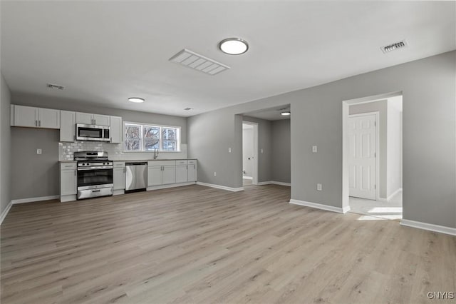 interior space with light countertops, visible vents, appliances with stainless steel finishes, open floor plan, and white cabinetry