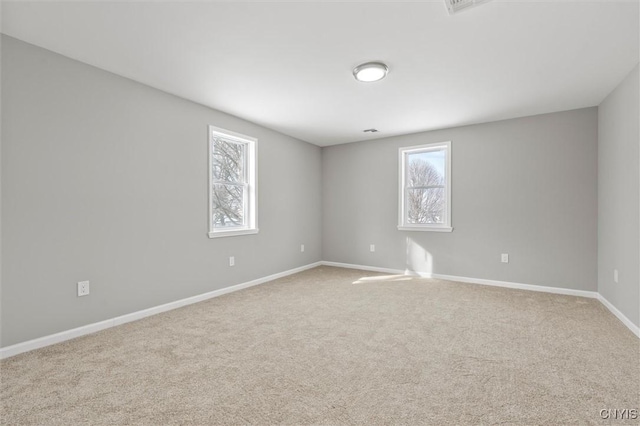 empty room featuring light carpet and baseboards