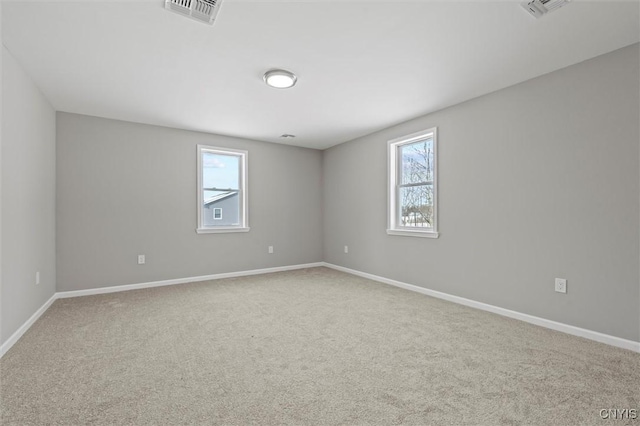 carpeted spare room featuring baseboards and visible vents