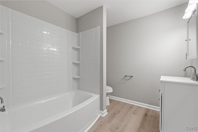 full bath with shower / bath combination, toilet, vanity, wood finished floors, and baseboards