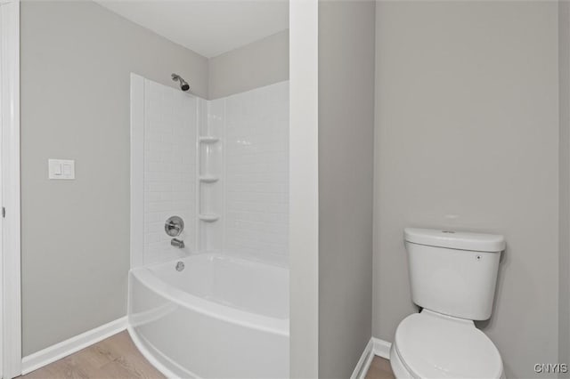 bathroom featuring toilet, baseboards, wood finished floors, and bathing tub / shower combination