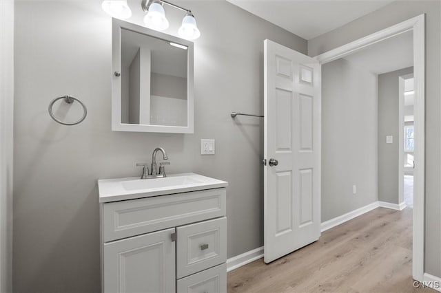 bathroom with baseboards, wood finished floors, and vanity