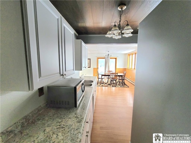 hallway featuring baseboard heating, an inviting chandelier, a sink, light wood-type flooring, and wooden ceiling