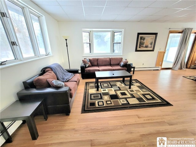 living room featuring light wood-style floors, a drop ceiling, and baseboard heating