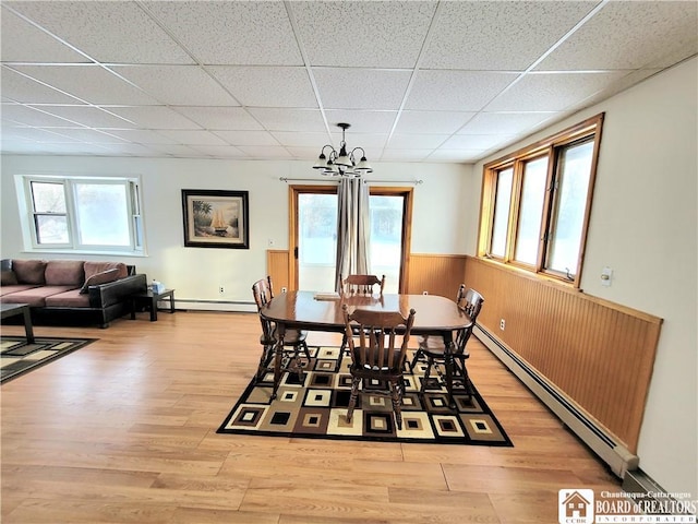 dining room with light wood-style floors, a baseboard radiator, and a drop ceiling