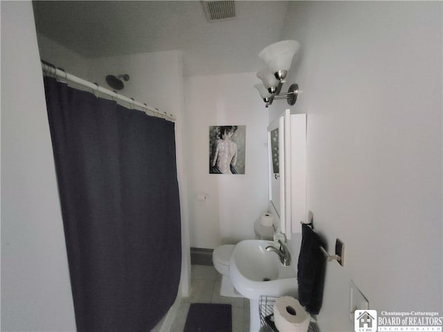 bathroom featuring curtained shower, visible vents, toilet, a sink, and tile patterned flooring