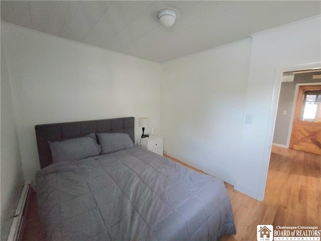 bedroom featuring light wood-style floors, baseboards, and ornamental molding