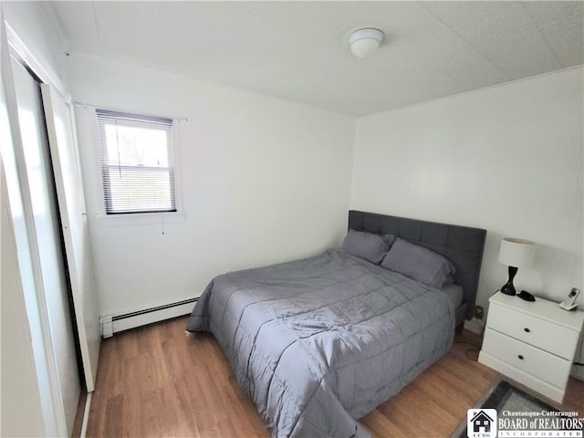 bedroom featuring light wood-style floors and baseboard heating