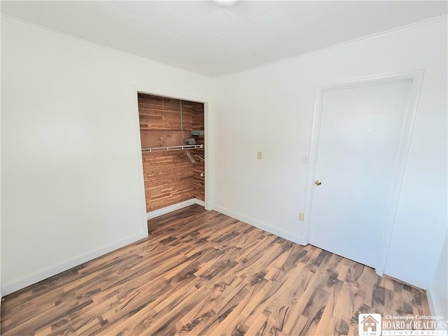 unfurnished room featuring baseboards, wood finished floors, and ornamental molding