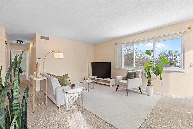 living area featuring visible vents, light colored carpet, a textured ceiling, and baseboards