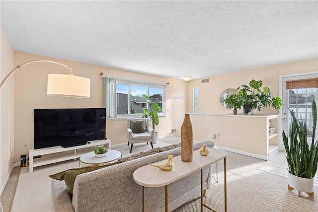 living room with a textured ceiling, visible vents, and baseboards